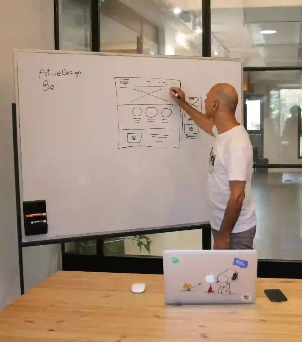 Concentrated male entrepreneur analyzing project standing near whiteboard in modern workspace