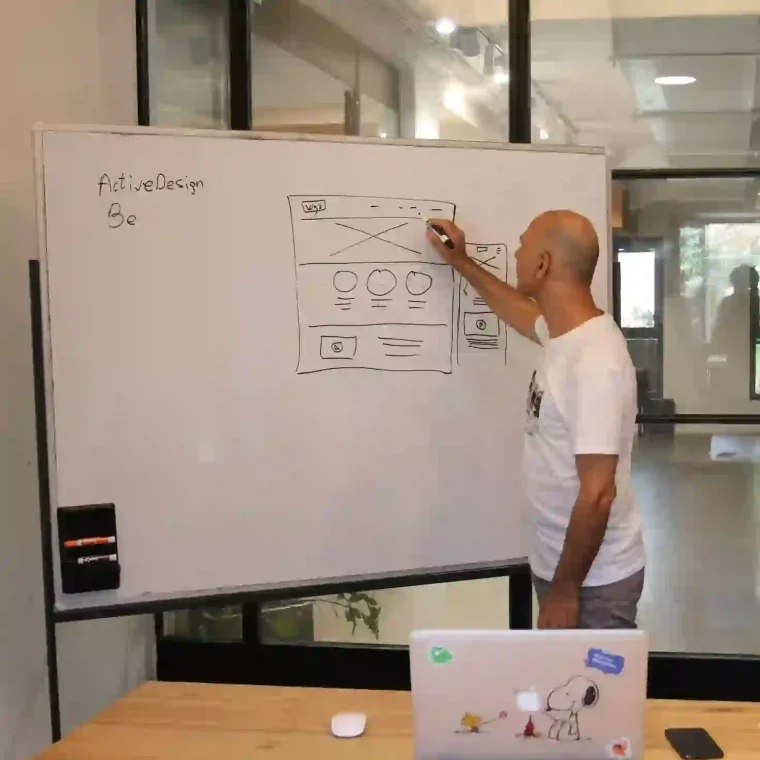 Concentrated male entrepreneur analyzing project standing near whiteboard in modern workspace